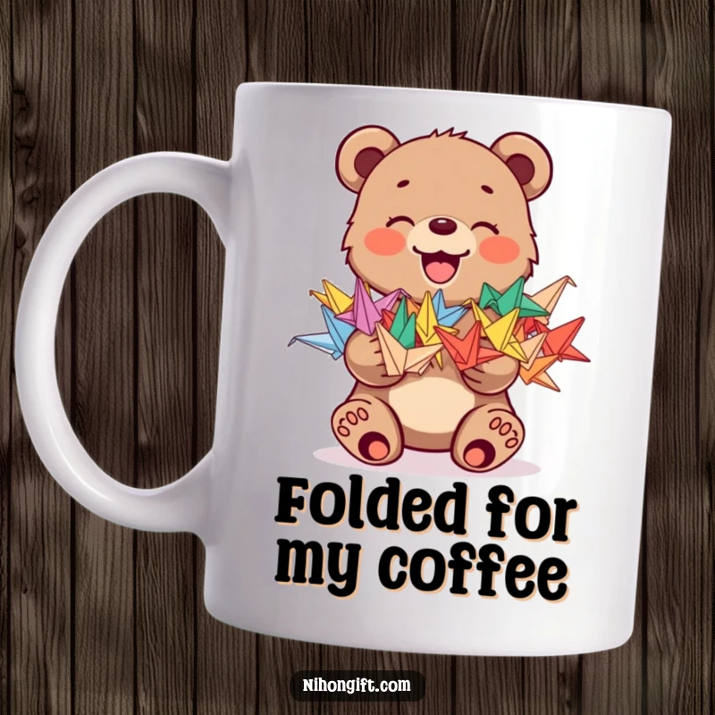 Funny mug featuring a joyful bear cub holding a stack of colorful origami cranes, symbolizing good luck and cheer.