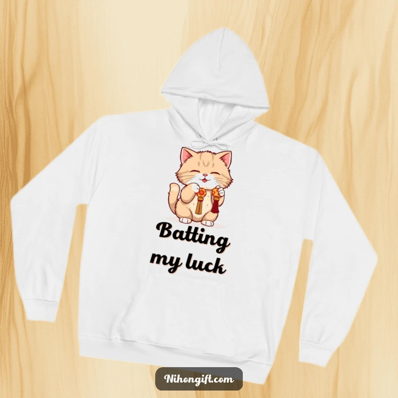 Funny cat hoodie showing a fluffy cat in a playful crouch, batting at a dangling lucky charm with playful intent.