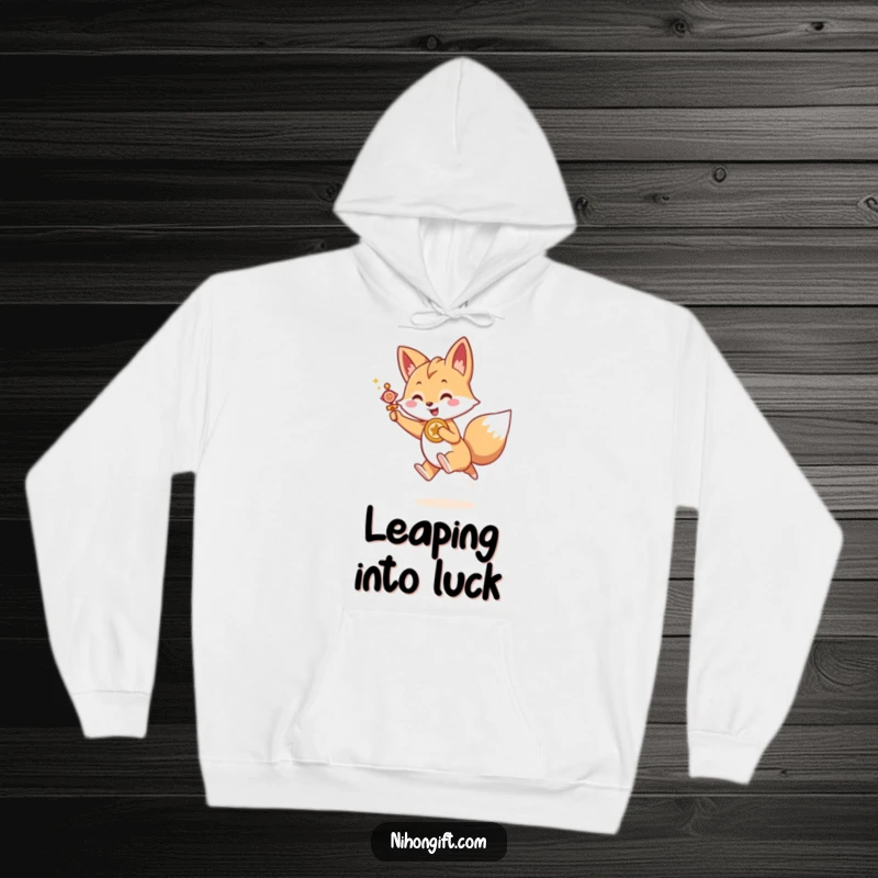 Funny Kawaii fox holding a lucky charm, joyfully leaping forward, on a cozy hoodie, a motivating funny gift.